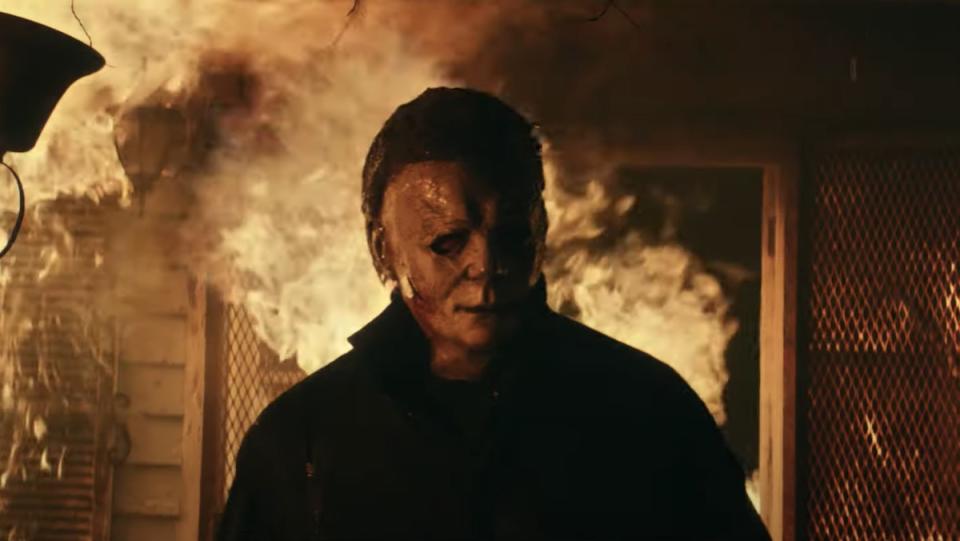 Michael Myers in his mask walks out of a burning home