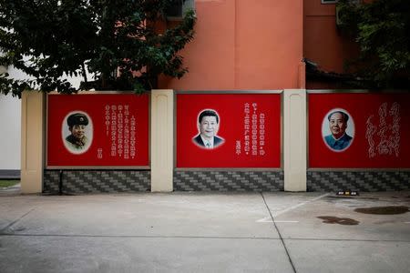 Pictures of late People's Liberation Army soldier Lei Feng, Chinese President Xi Jinping and late Chinese Chairman Mao Zedong overlook a courtyard in Shanghai, China, September 26, 2017. The quotes read: "Lei Feng?There is a limit to one's life, but there is no limit to serving the people. I would devote my limited life to limitlessly serving the people. Xi Jinping: Be a seed of Lei Feng spirit, and let it be widely promoted in the motherland. Mao Zedong: Learn from Comrade Lei Feng" Picture taken September 26, 2017. REUTERS/Aly Song