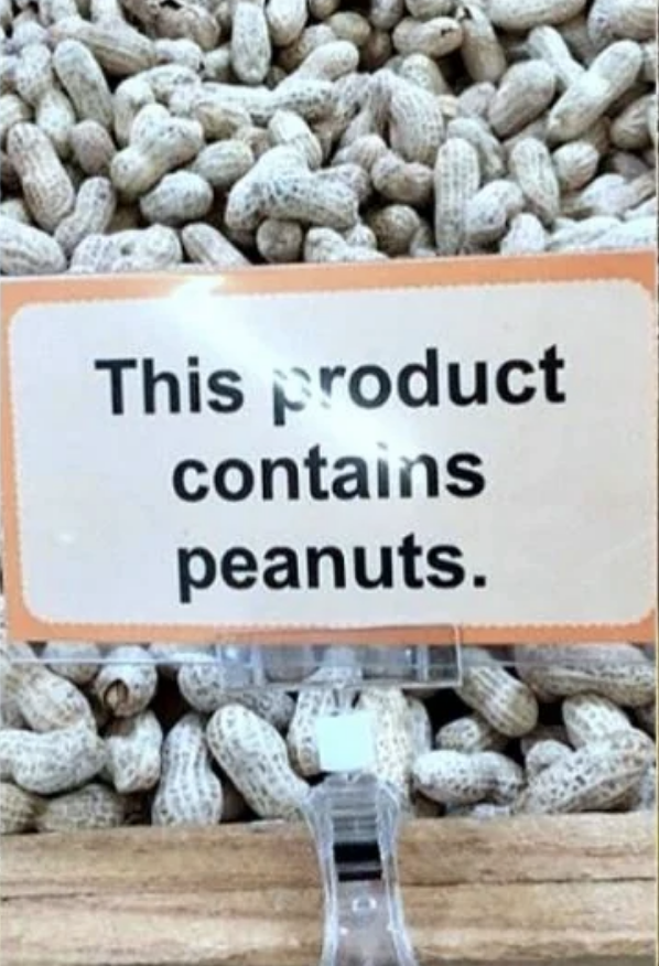 A sign in front of a pile of peanuts that reads: 