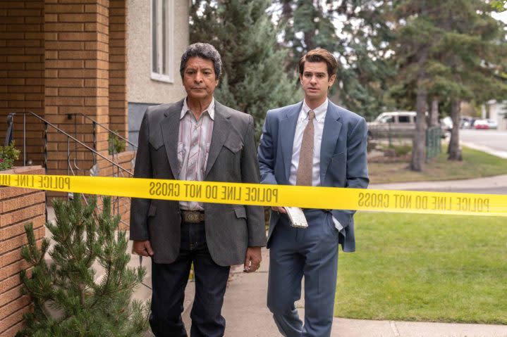 Gil Birmingham and Andrew Garfield walk toward crime scene tape in Under the Banner of Heaven.