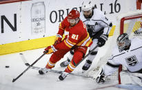 Los Angeles Kings goalie David Rittich (31) swats the puck away from Calgary Flames forward Kevin Rooney (21) as defenseman Drew Doughty (8) trails during the first period of an NHL hockey game Saturday, March 30, 2024, in Calgary, Alberta. (Jeff McIntosh/The Canadian Press via AP)