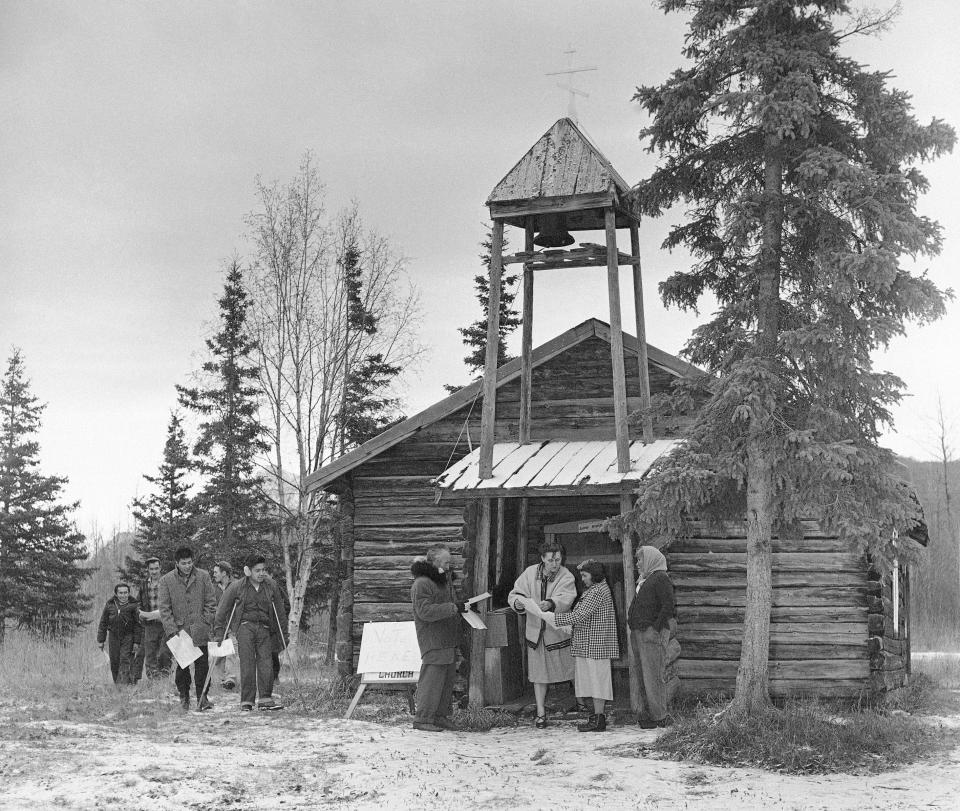 FILE - Olga Johnson, in light jacket, an election judge, explains a sample ballot to Eklutna residents as they arrive to cast their first presidential election ballots at St. Nicholas Church in Eklutna, Alaska, a year after Alaska gained statehood, on Nov. 8, 1960. A restoration project has started at the church on Oct. 13, 2023, which is the oldest standing building in the Municipality of Anchorage. (AP Photo/File)