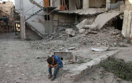 A boy sits near rubble of damaged buildings in Arbin, a town in the Damascus countryside, Syria July 25, 2017. REUTERS/Bassam Khabieh