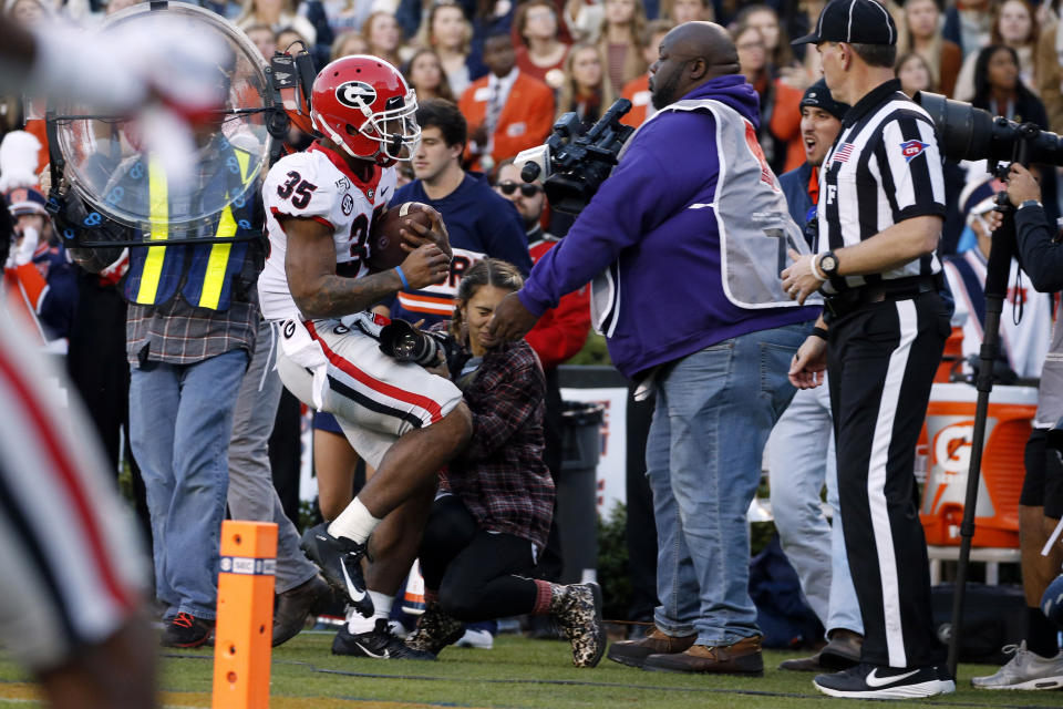 Georgia running back Brian Herrien (35) runs out of bounds and into a photographer during the first half of an NCAA college football game against Auburn, Saturday, Nov. 16, 2019, in Auburn, Ala. (AP Photo/Butch Dill)