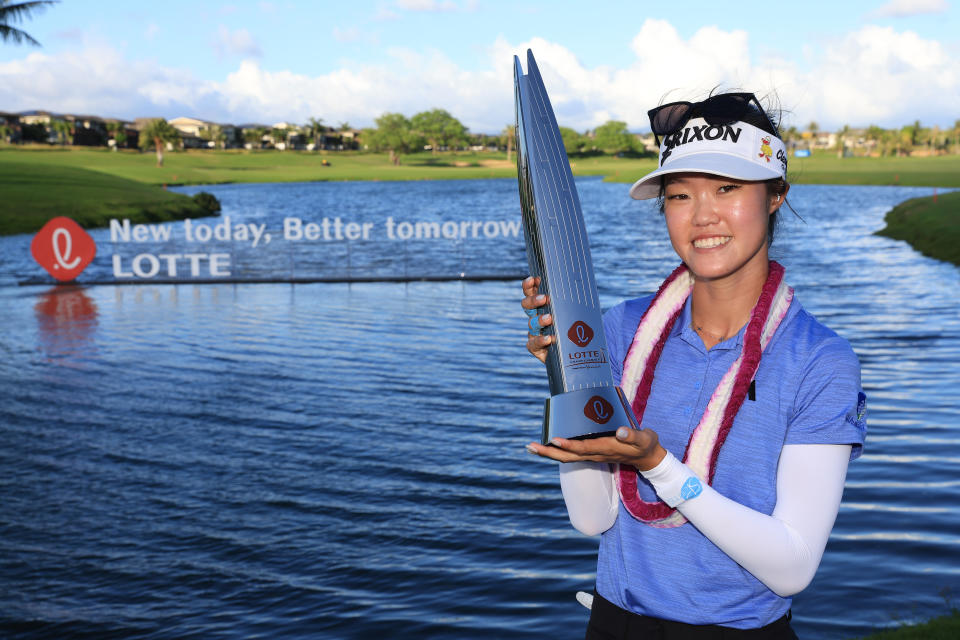 Kim holds the trophy in front of a tournament advert board