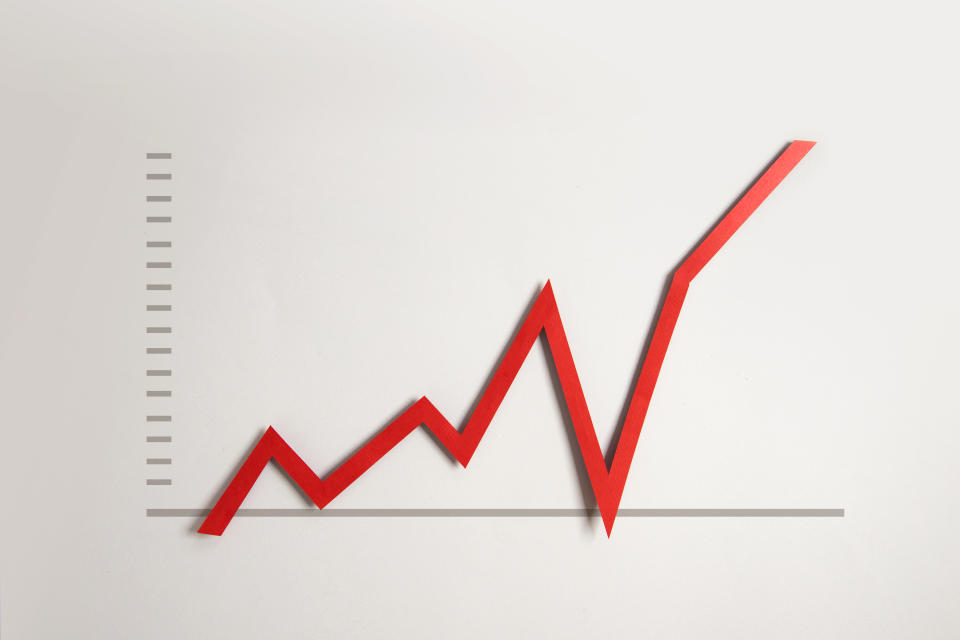 Hand pulling business or finance red growth chart line upwards on grey background.