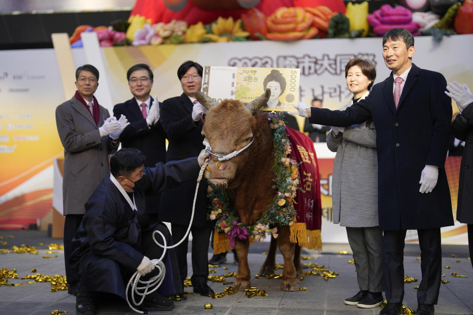 South Korean financial officers pose with a bull to celebrate the opening for the Year 2023 trading outside of the Korea Exchange in Seoul, South Korea, Monday, Jan. 2, 2023. (AP Photo/Lee Jin-man)