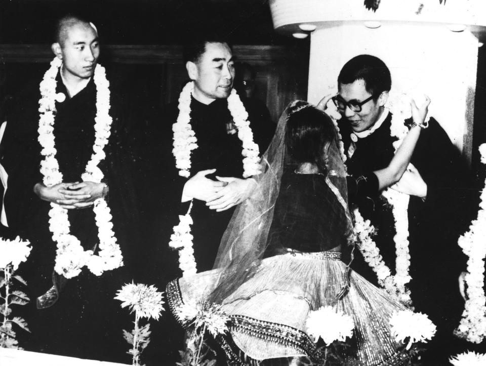 The Dalai Lama (right) the Panchen Lama (left) and the Chinese Prime Minister Chou En Lai (middle) during a visit to India in 1956. An Indian dancer is adorning the guests with garlands of flowers.