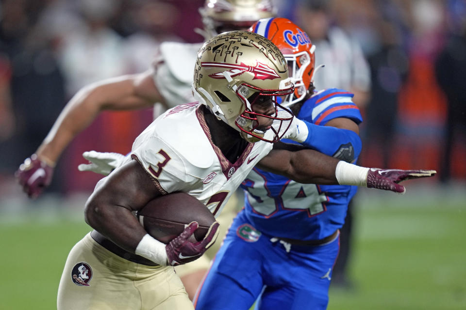 Florida State running back Trey Benson (3) looks to get past Florida linebacker Mannie Nunnery (34) during the first half of an NCAA college football game Saturday, Nov. 25, 2023, in Gainesville, Fla. (AP Photo/John Raoux)