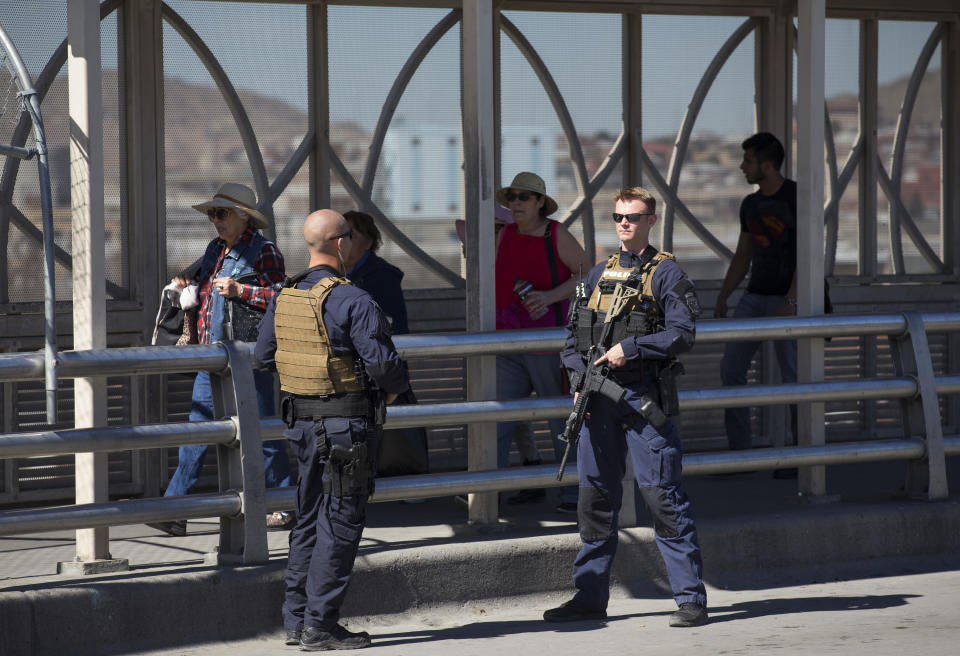 FILE - In this Feb. 16, 2016, file photo, pedestrians cross into Juarez, Mexico as U.S. Customs and Border Protection officers of the Special Response Team unit, patrol the Paso del Norte Port of Entry in El Paso, Texas. The state of California is freeing up to $28 million to assist immigrants arriving at the state's border with Mexico to be released with notices to appear in court, marking a sharp contrast with other border states that have emerged as foes of President Joe Biden's immigration policies.(AP Photo/Ivan Pierre Aguirre, File)