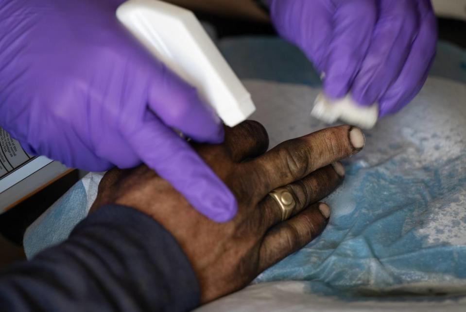 Valley Streetz Harm Reduction physician Dr. James Kraus helps James Black with an open wound on his hand in Modesto, Calif., Friday, April 12, 2024. The program provides harm reduction services and medical treatment at The Rock Church on Friday mornings.