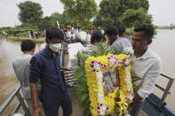 CORRECTS TO SAY EAST OF PHNOM PENH, NOT EASTERN - A portrait photo of a teen victim, Chanda July, is carried by her relative during her funeral procession in Koh Chamroeun village, east of Phnom Penh, Cambodia, Friday, Oct. 14, 2022. Multiple students in southern Cambodia who were crossing a river have died after the boat they were on capsized Thursday night, officials said. (AP Photo/Heng Sinith)