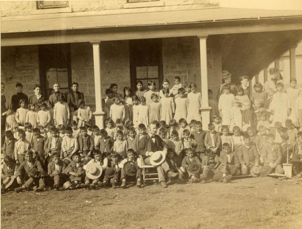 Superintendent Thomas W Conway sits with a large group at the Pawnee Boarding School in the late 1800s.