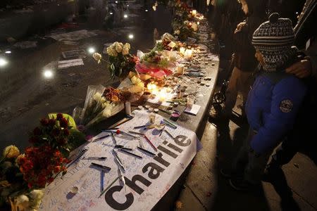 People gather to place candles, flowers and pencils, as they continue to pay tribute to the shooting victims on Wednesday at the satirical weekly Charlie Hebdo, at the Republique square in Paris January 10, 2015. REUTERS/Pascal Rossignol