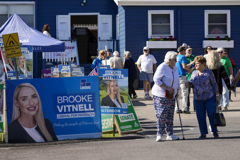 People stand outside a polling station in Nelson Bay, Australia, Monday, May 9, 2022. Early voting has begun in Australia's federal election with the opposition party hoping the first ballots will reflect its lead over the government in an opinion poll. (AP Photo/Mark Baker)