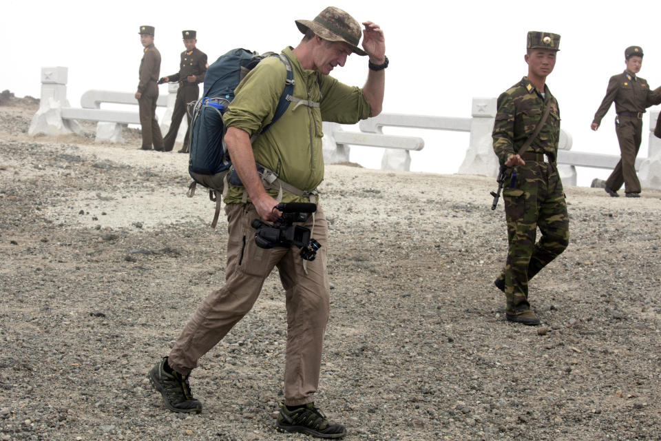 In this Saturday, Aug. 18, 2018, photo, Roger Shepherd of Hike Korea walks past North Korean soldiers while leading a hike on Mount Paektu in North Korea. Hoping to open up a side of North Korea rarely seen by outsiders, Shepherd, a New Zealander who has extensive experience climbing the mountains of North and South Korea is leading the first group of foreign tourists allowed to trek off road and camp out under the stars on Mount Paektu, a huge volcano that straddles the border that separates China and North Korea. (AP Photo/Ng Han Guan)