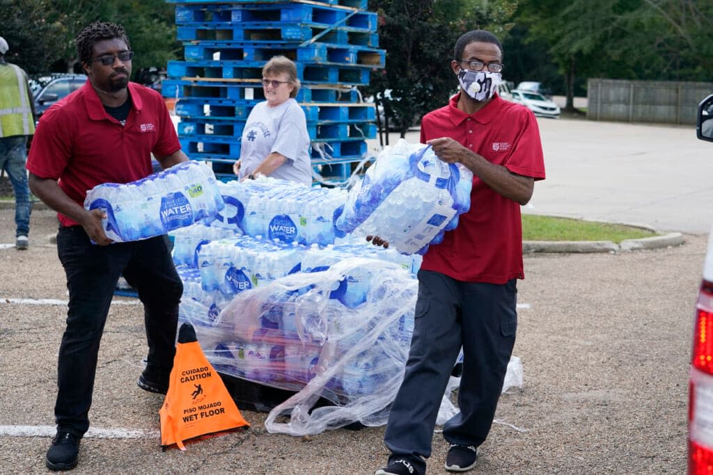 Salvation Army members carry cases of water to a waiting vehicle in Jackson, Miss., Wednesday, Aug. 31, 2022. The organization and a local Walmart store established a mid-morning distribution site to assist water needy residents. (AP Photo/Rogelio V. Solis)