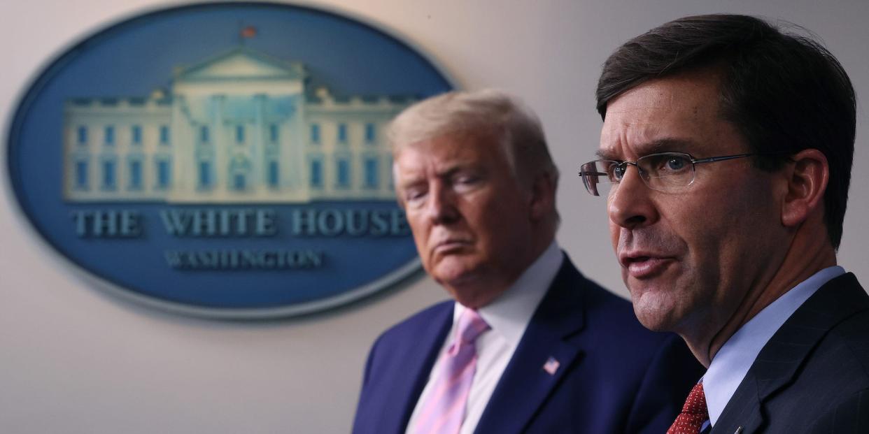 Mark Esper speaking as Donald Trump looks on at a White House briefing