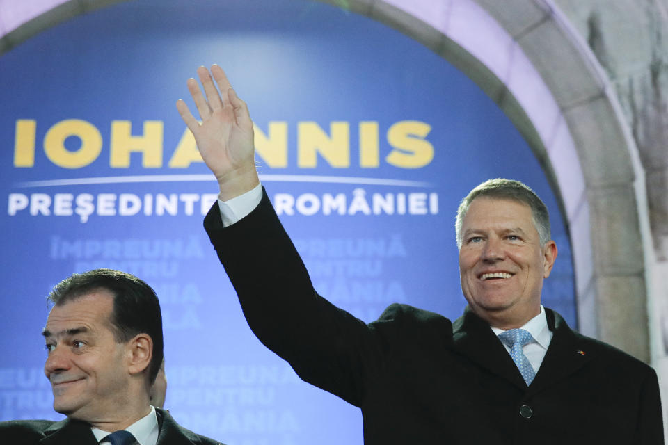 Romanian President Klaus Iohannis, right, waves next to Romanian prime minister Ludovic Orban, after exit polls were published, in Bucharest, Romania, Sunday, Nov. 24, 2019. An exit poll by the IRES independent think tank showed Iohannis getting 66.5 % of the votes, with 33.5% for Social Democratic Party leader Viorica Dancila, a former prime minister. (AP Photo/Vadim Ghirda)