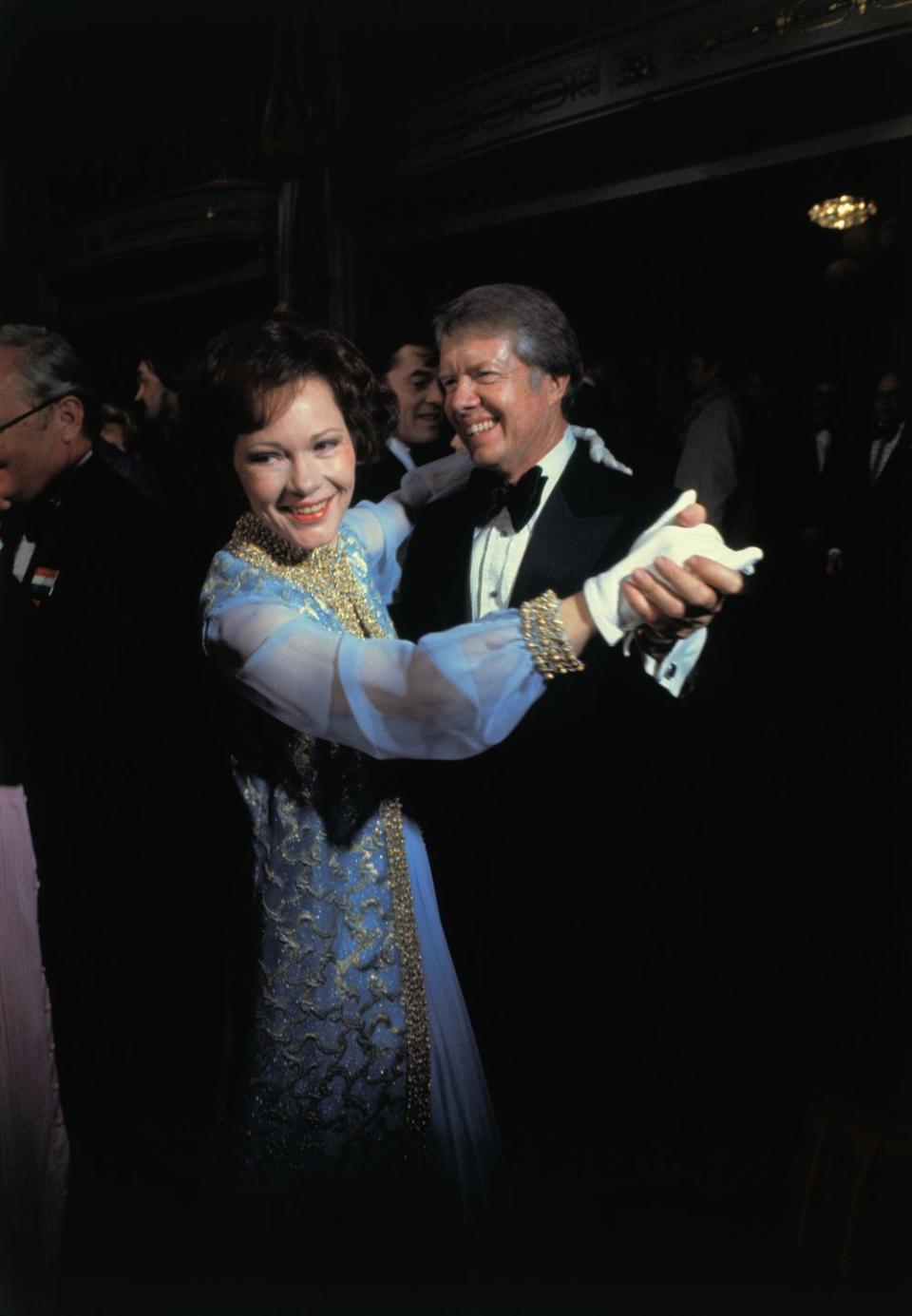 <p>The couple share a dance at the inaugural ball in 1977. Rosalynn Carter wears an elaborate blue chiffon evening gown with gold brocade detailing. Her dress and jacket were <a href="https://americanhistory.si.edu/first-ladies/rosalynn-carter" rel="nofollow noopener" target="_blank" data-ylk="slk:designed by Mary Matise for Jimmae;elm:context_link;itc:0;sec:content-canvas" class="link ">designed by Mary Matise for Jimmae</a>. </p>