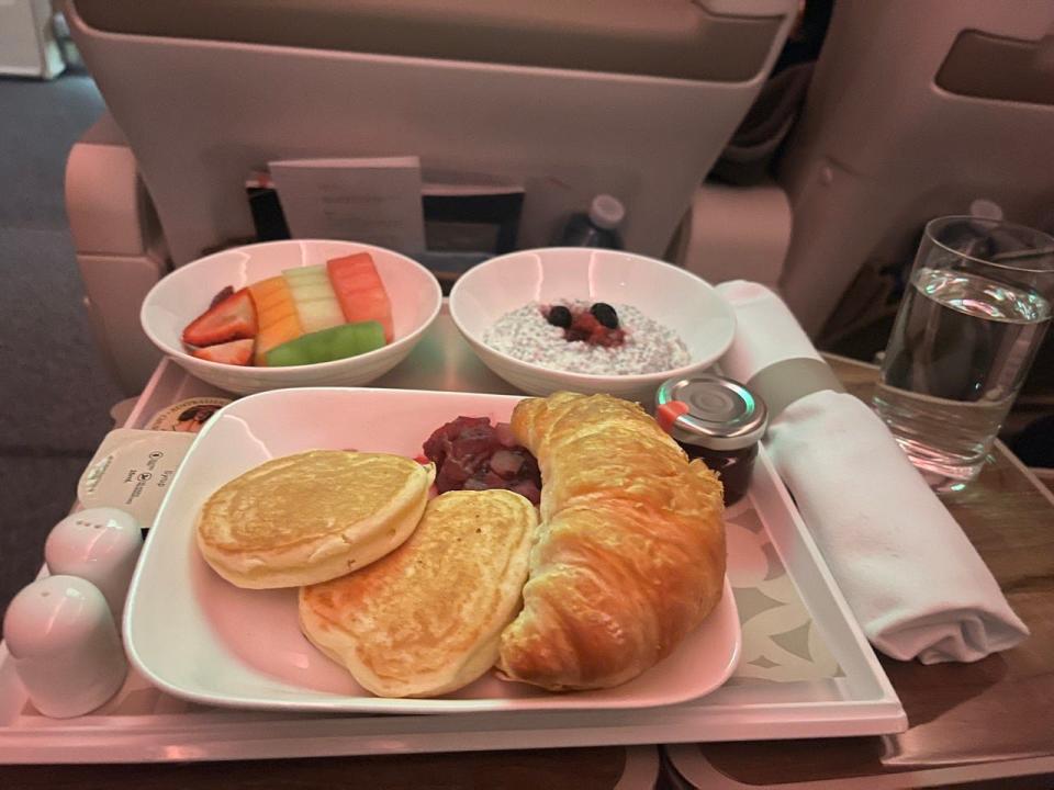 Frühstück im Flugzeug mit Croissant und Pfannkuchen auf dem Teller 