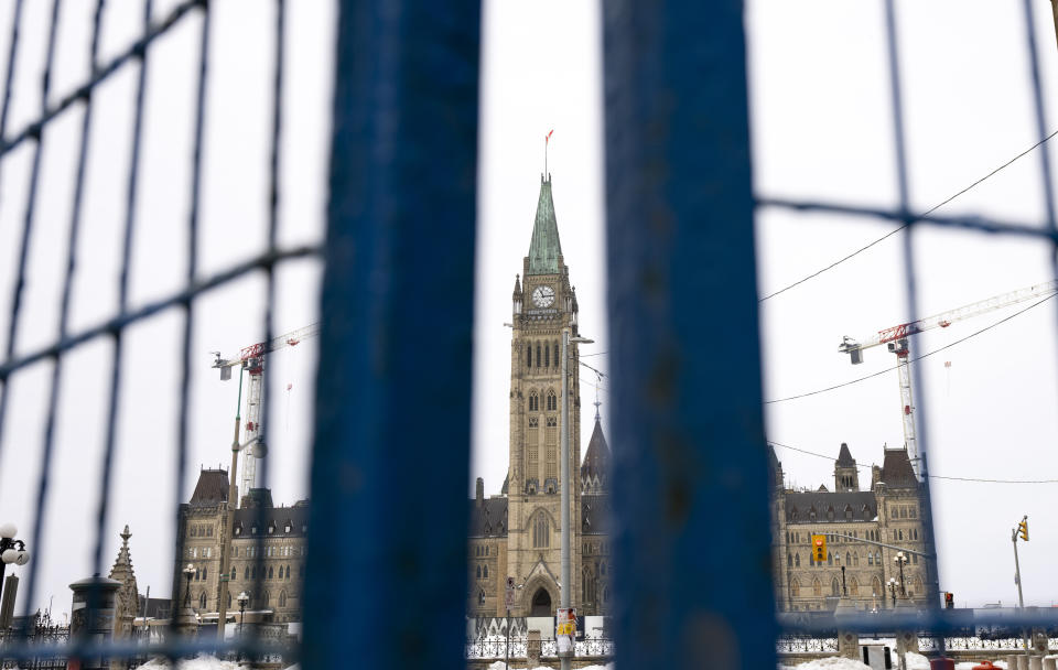 The Peace tower is seen between panels of temporary fencing, Wednesday, Feb. 23, 2022 in Ottawa. Ottawa protesters who vowed never to give up are largely gone, chased away by police in riot gear in what was the biggest police operation in the nation’s history. (Adrian Wyld /The Canadian Press via AP)