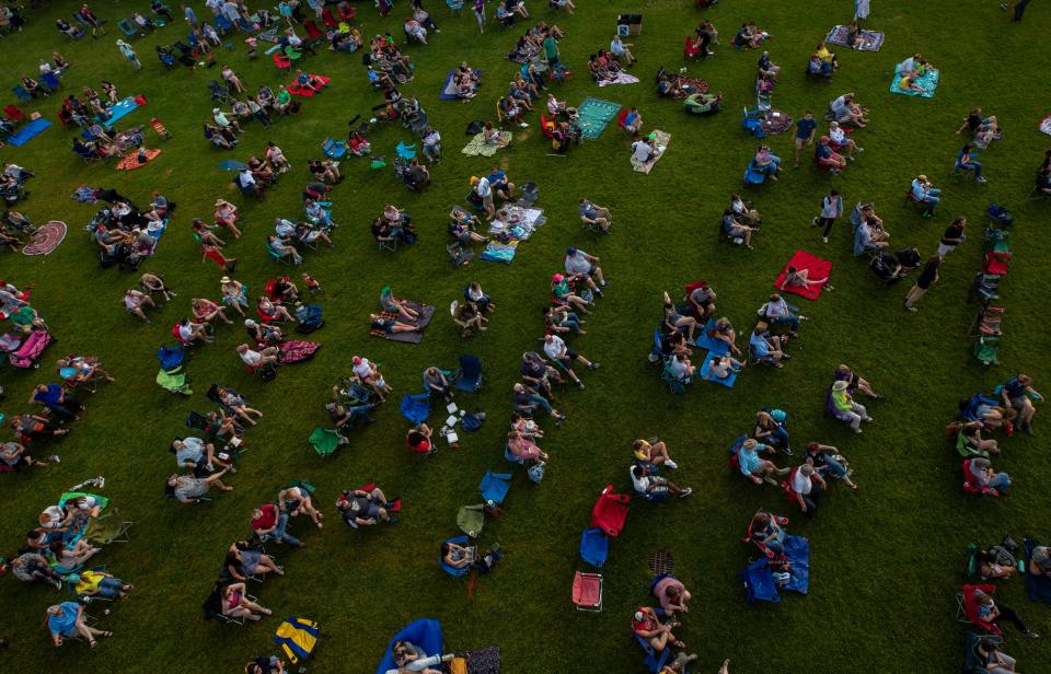 Spectators take seats in the grass just out from under the Big Four Bridge during  the second Waterfront Wednesday of the year. May 29, 2019