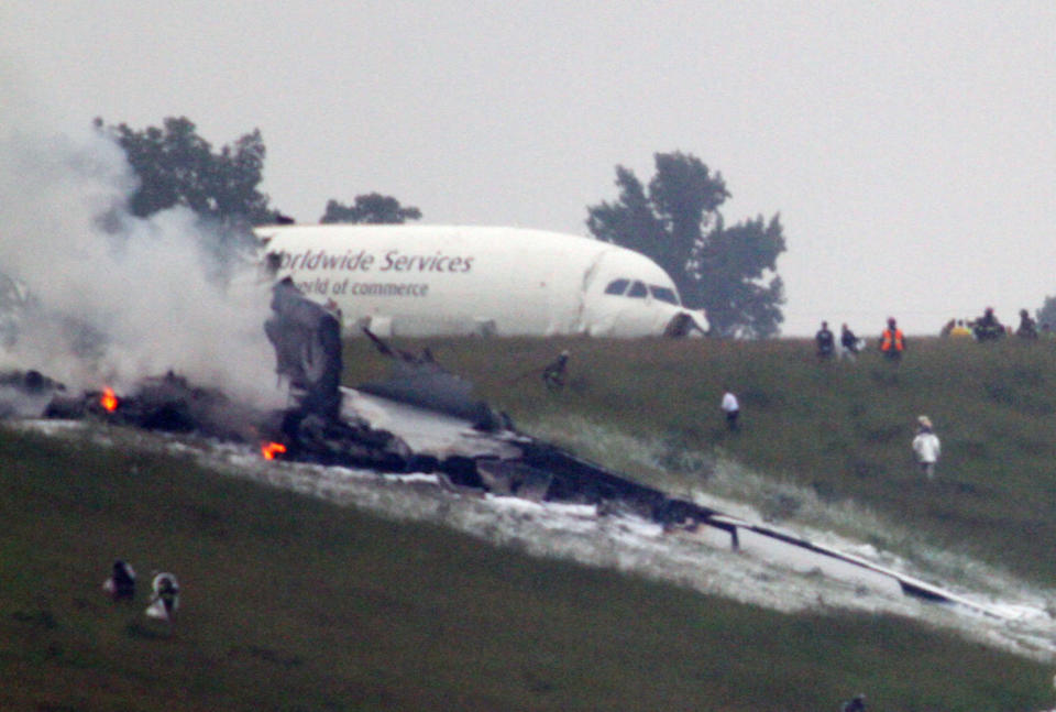 Debris burns as a UPS cargo plane lies on a hill at Birmingham-Shuttlesworth International Airport after crashing on approach, Wednesday, Aug. 14,  2013, in Birmingham, Ala. Toni Herrera-Bast, a spokeswoman for Birmingham's airport authority, says there are no homes in the immediate area of the crash. (Hal Yeager/AP)