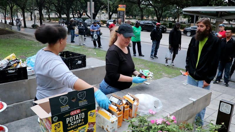 Food Not Bombs volunteer Shere Dore prepares a plate of food for a man in Houston, TX