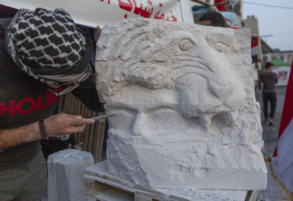 In this Tuesday, Dec. 17, 2019, photo, young Iraqi trainees work on sculptures in preparation for their upcoming art exhibition, during the ongoing protests in Tahrir square, Baghdad, Iraq. Tahrir Square has emerged as a focus of the protests, with protesters camped out in dozens of tents. Dozens of people took part in the simple opening of the sculpture exhibition. (AP Photo/Nasser Nasser)