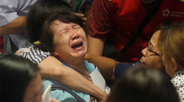 Relatives of passengers of the missing AirAsia flight QZ 8501 react to the news on television about the findings of bodies on the waters near the site where the jetliner disappeared. Photo: AP