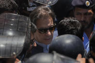 Pakistan's former Prime Minister Imran Khan, center, is escorted by police officers as he arrives to appear in a court, in Islamabad, Pakistan, Friday, May 12, 2023. A high court in Islamabad has granted former Prime Minister Imran Khan a two-week reprieve from arrest in a graft case and granted him bail on the charge. (AP Photo/Anjum Naveed)
