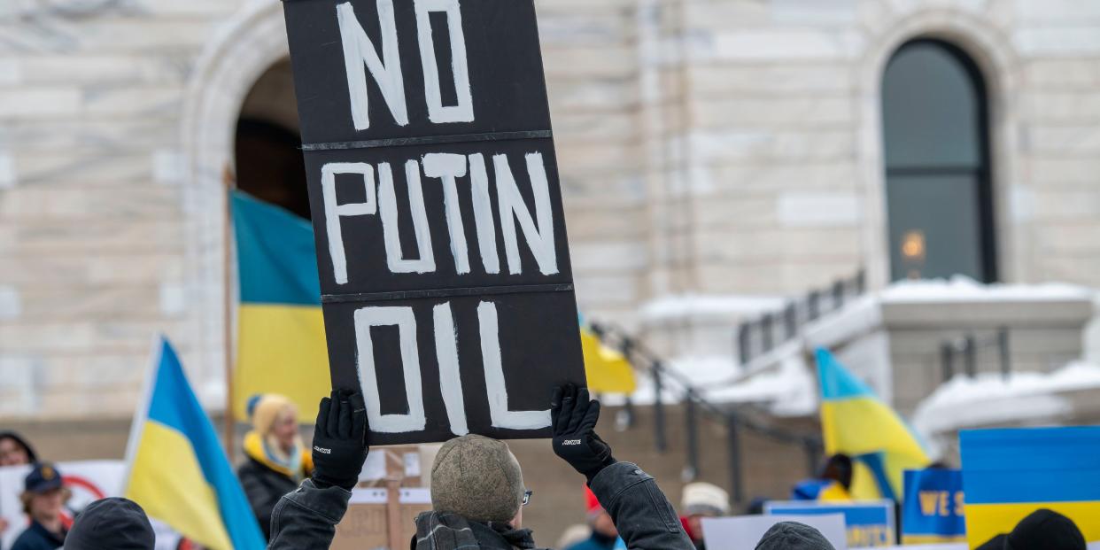 A protestor holding up a signboard "No Putin Oil" among Ukraine flags