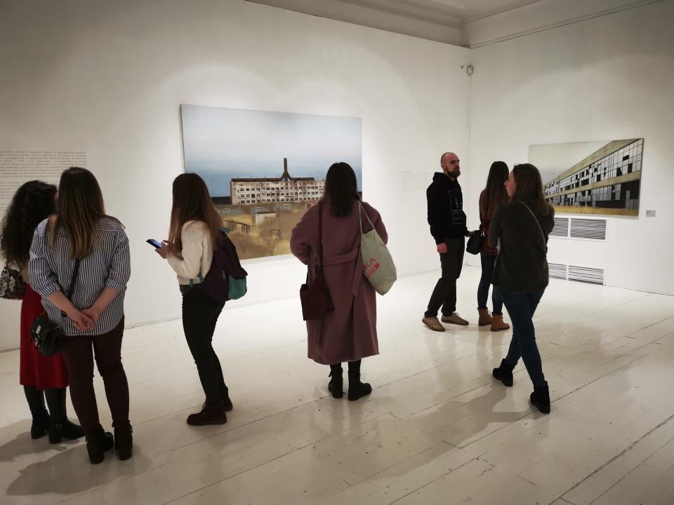 In this photo taken on Sunday, Feb. 17, 2019, visitors attend an exhibition by Russian artist Pavel Otdelnov in Moscow, Russia . Pavel Otdelnov, a Russian artist who grew up in Dzerzhinsk, the center of the nation's chemical industries 355 kilometers (220 miles) east of Moscow, focused on the city, one of the most polluted in Russia, in his new 'Promzona' art show. (AP Photo/Ivan Kochkarev)