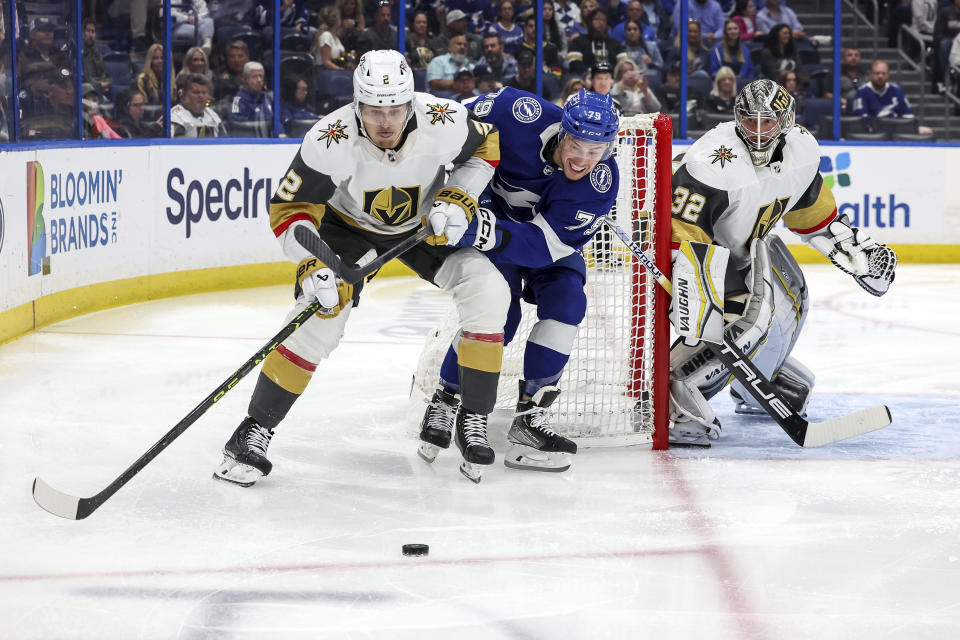 Vegas Golden Knights' Zach Whitecloud (2) avoids the check of Tampa Bay Lightning's Ross Colton (79) behind goaltender Jonathan Quick during the second period of an NHL hockey game Thursday, March 9, 2023, in Tampa, Fla. (AP Photo/Mike Carlson)