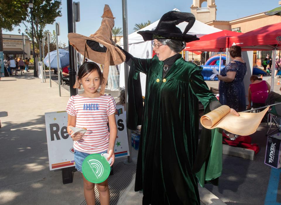 Cosplayer Sindiroo Sheth portraying Professor McGonagall from Harry Potter, places at the Sorting Hat on Vinienne Joutrain, 8, of South San Francisco at the Great Valley BookFest at the Promenade Shops at the Orchard Valley Shopping Center in Manteca on Saturday, Oct. 8, 2022.  The event, which promotes and celebrates literacy, benefits Friends of the Library, read Valley Writing Camps, Give Every Child a Chance and the San Joaquin County Office of Education.  