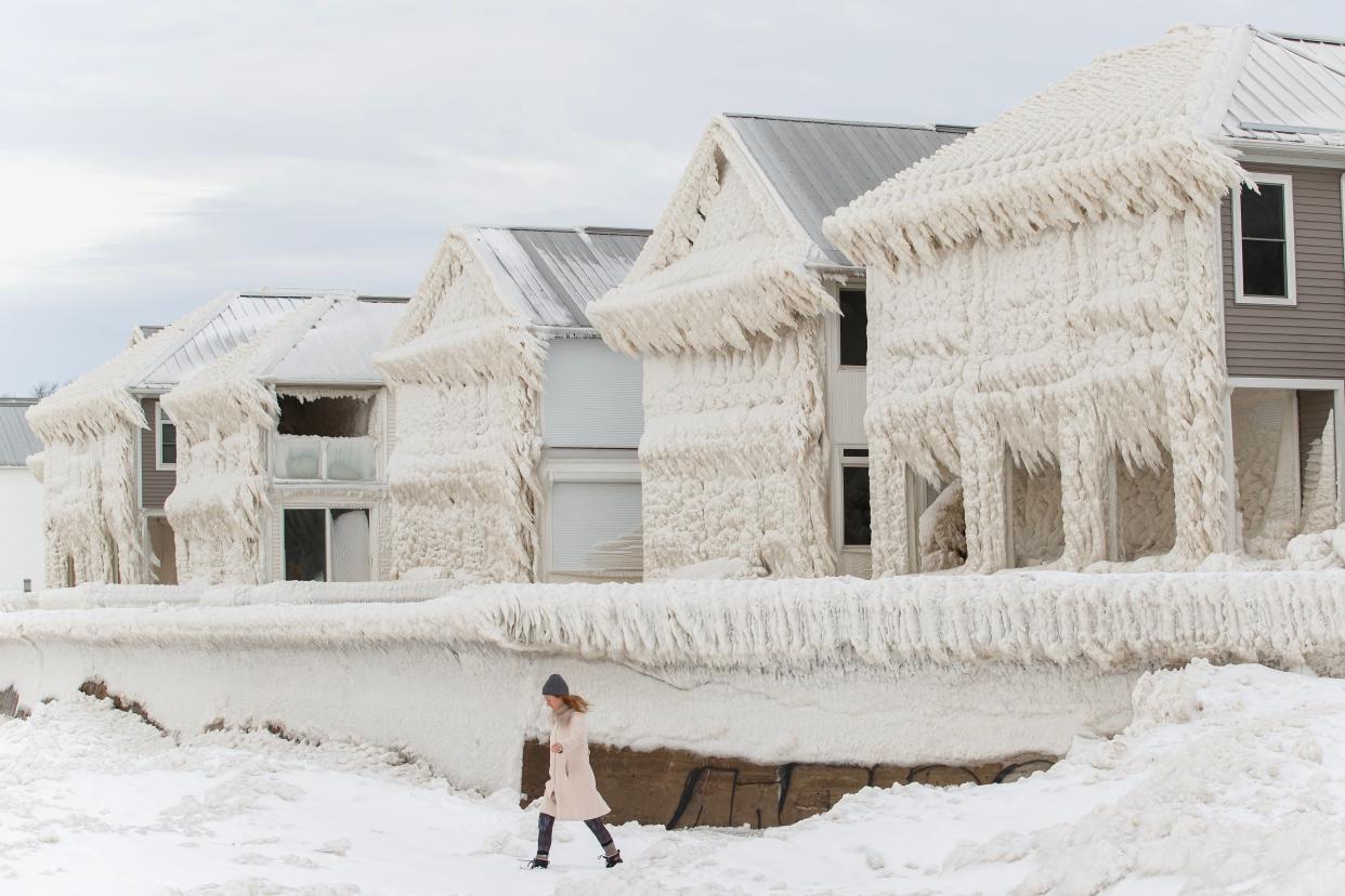 TOPSHOT - A person walks by homes covered in ice at the waterfront community of Crystal Beach in Fort Erie, Ontario, Canada, on December 28, 2022, following a massive snow storm that knocked out power in the area to thousands of residents. (Photo by Cole Burston / AFP) (Photo by COLE BURSTON/AFP via Getty Images)
