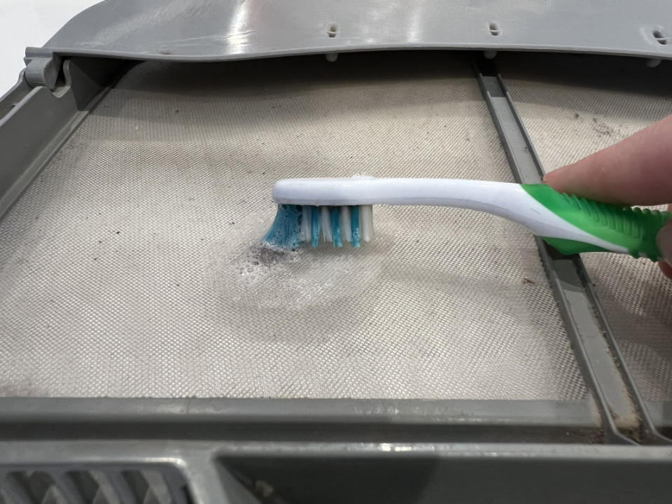 Removing lint buildup on screen with a soft toothbrush.<p>Emily Fazio</p>