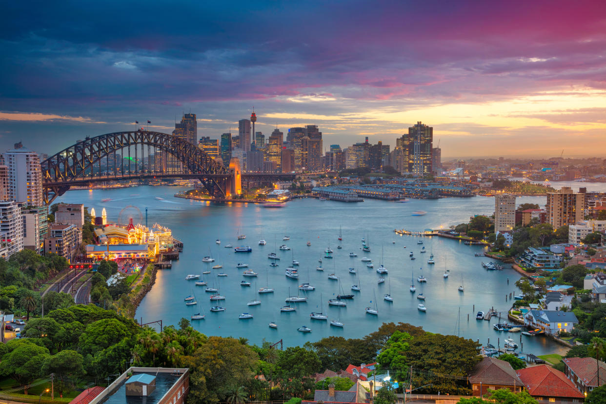 Cityscape image of Sydney, Australia with Harbour Bridge and Sydney skyline during sunset.