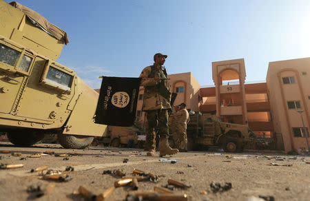 An Iraqi soldier holds an Islamic State flag during a battle with Islamic State militants, north of Mosul, Iraq. REUTERS/Ari Jalal