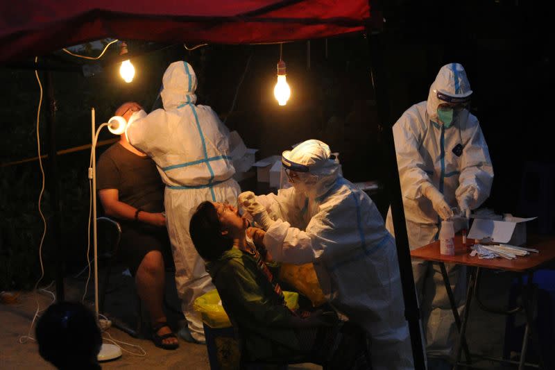 Workers collect swabs for nucleic acid testing at a makeshift testing site in Dalian