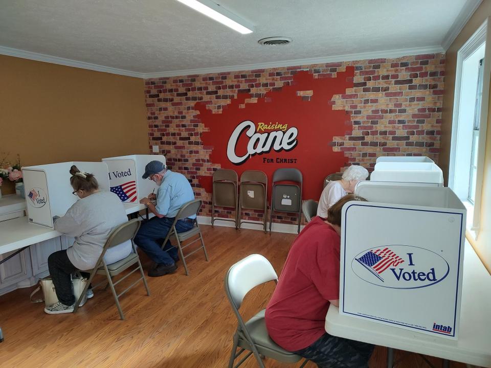 Six booths awaited voters by a mural that reads "Raising Cane For Christ" at First Free Will Baptist Church in Pearl, Miss., on Election Day, Tuesday, Nov. 7.