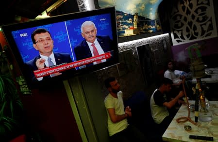 People watch a televised debate between Istanbul's mayoral candidates Imamoglu of CHP and Yildirim of AKP at a cafe in central Istanbul