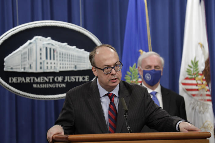 Jeffrey Clark stands at a podium near Jeffrey Rosen, who is wearing a face mask, in front of flags and a blue backdrop bearing a seal that reads: Department of Justice, Washington.