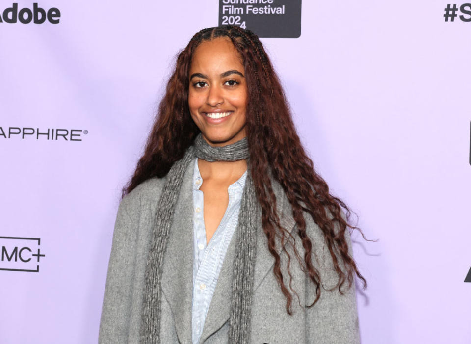 Malia on red carpet, wearing a scarf and blazer, hair styled long