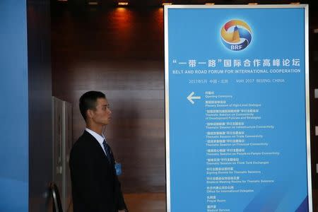 A staff member stands next to a sign for the Belt and Road Forum at the National Convention Centre in Beijing, China May 13, 2017. REUTERS/Stringer/Files