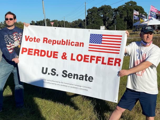 PHOTO: Two demonstrators hold a sign urging Trump supporters to vote for Republican U.S. Senators Kelly Loeffler and David Perdue in runoff elections in Valdosta, Ga., Dec.5, 2020. (Nathan Layne/Reuters)