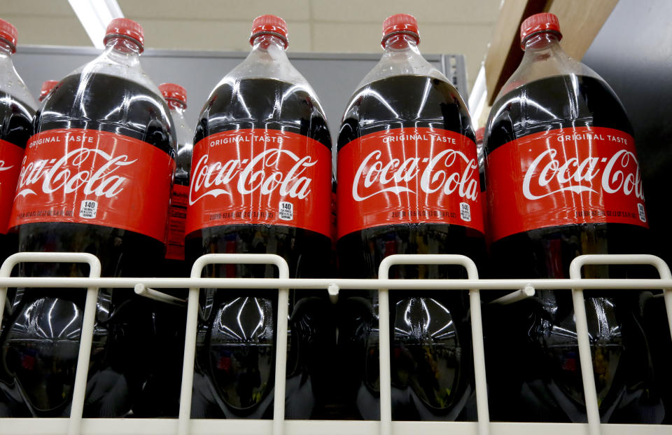 FILE- In this Aug. 8, 2018, file photo bottles of Coca-Cola sit on a shelf in a market in Pittsburgh. The Coca-Cola Co. reports earnings Tuesday, Oct. 30. (AP Photo/Gene J. Puskar, File)