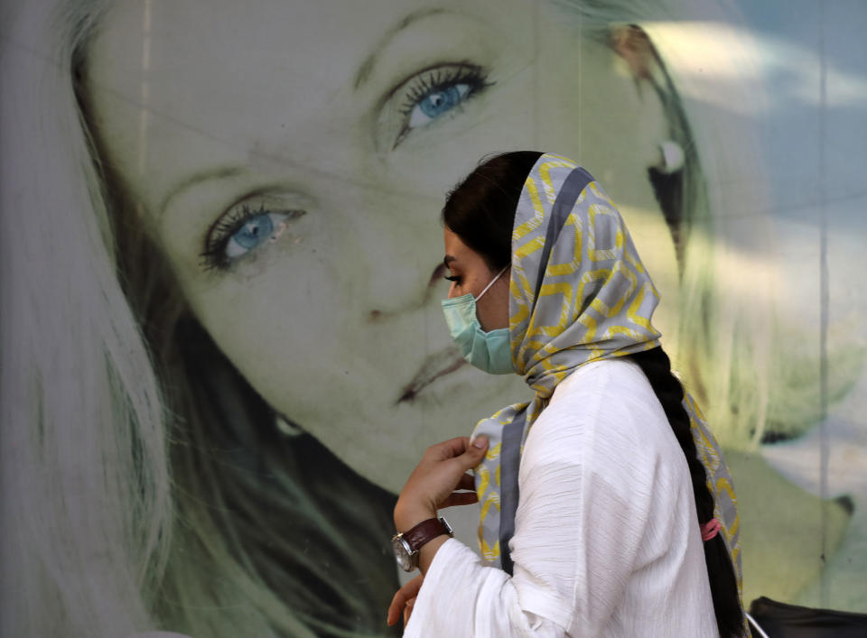 A woman wearing protective face mask to help prevent the spread of the coronavirus walks past an advertisement of skin care products in southern Tehran, Iran, Tuesday, July 20, 2021. Iran on Tuesday broke another record in the country's daily new coronavirus cases, even as Tehran and its surroundings went into lockdown, a week-long measure imposed amid another surge in the pandemic. (AP Photo/Vahid Salemi)