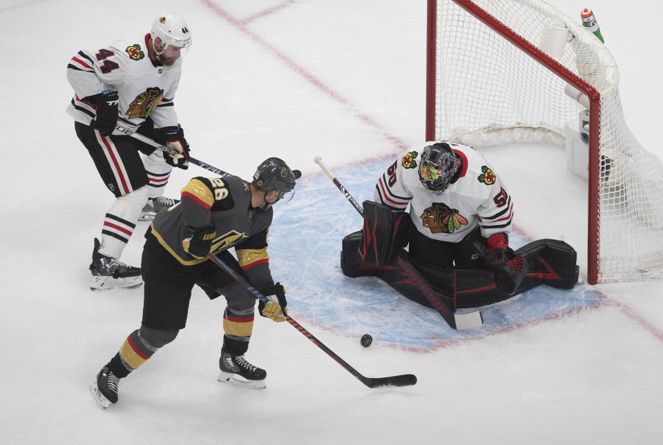 Chicago Blackhawks goalie Corey Crawford (50) makes the save on Vegas Golden Knights' William Carrier (28) as Blackhawks' Calvin de Haan (44) defends during the second period in Game 1 of an NHL hockey Stanley Cup first-round playoff series, Tuesday, Aug. 11, 2020, in Edmonton, Alberta. (Jason Franson/The Canadian Press via AP)